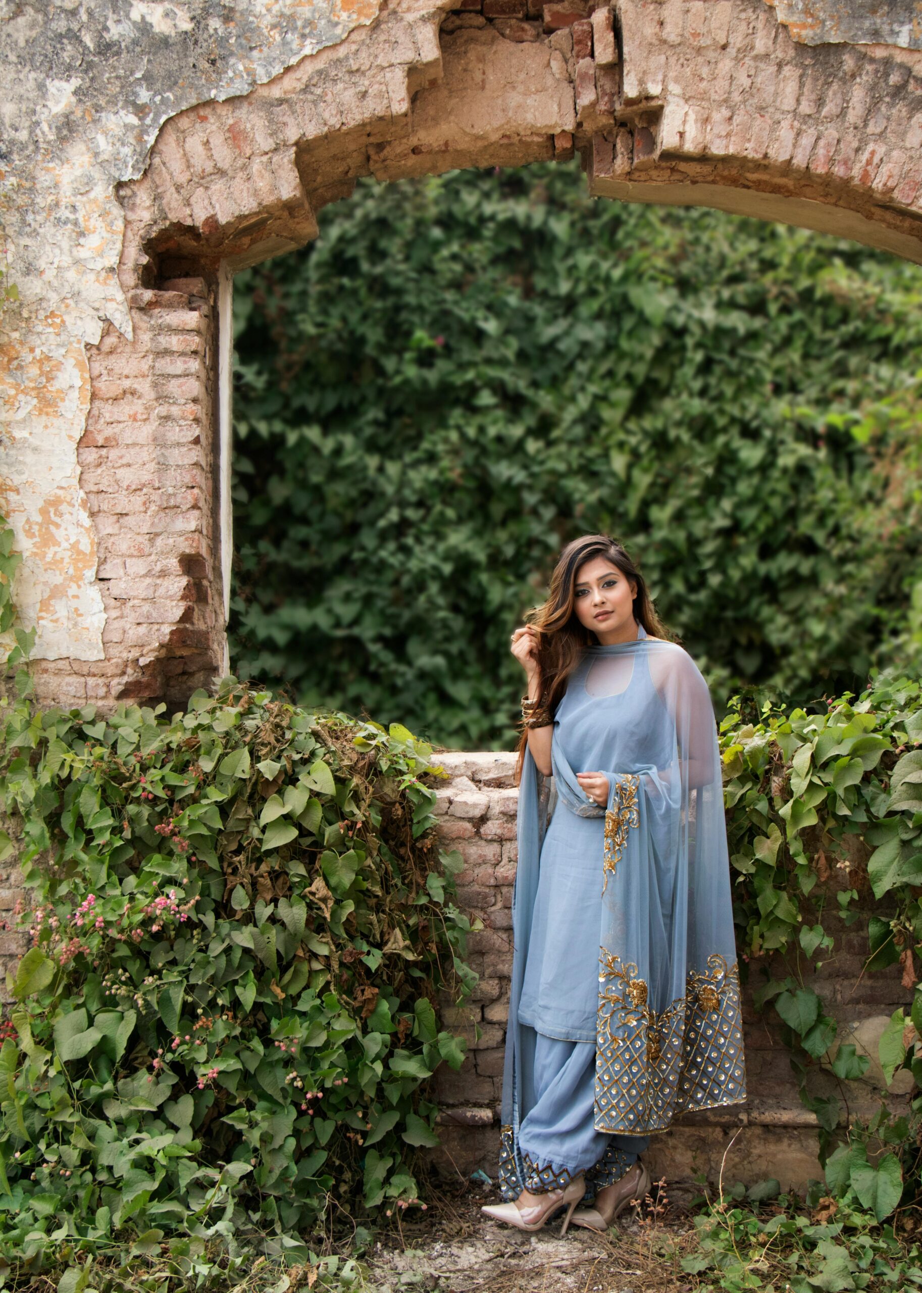 Woman in Blue Dress Standing Near Brown Concrete Bricks